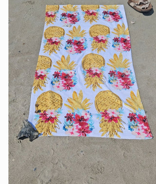 Beach towel with pineapple and floral pattern on sand