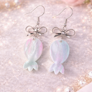 Pastel candy bow drop earrings with silver hardware on marble background