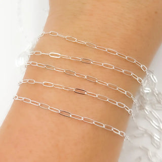 Silver chain necklace on a wrist with a white background to show the chain up close