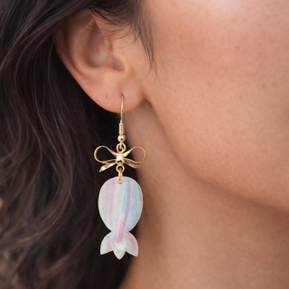 Pastel upside-down pineapple and bow drop earrings with gold hardware on marble background